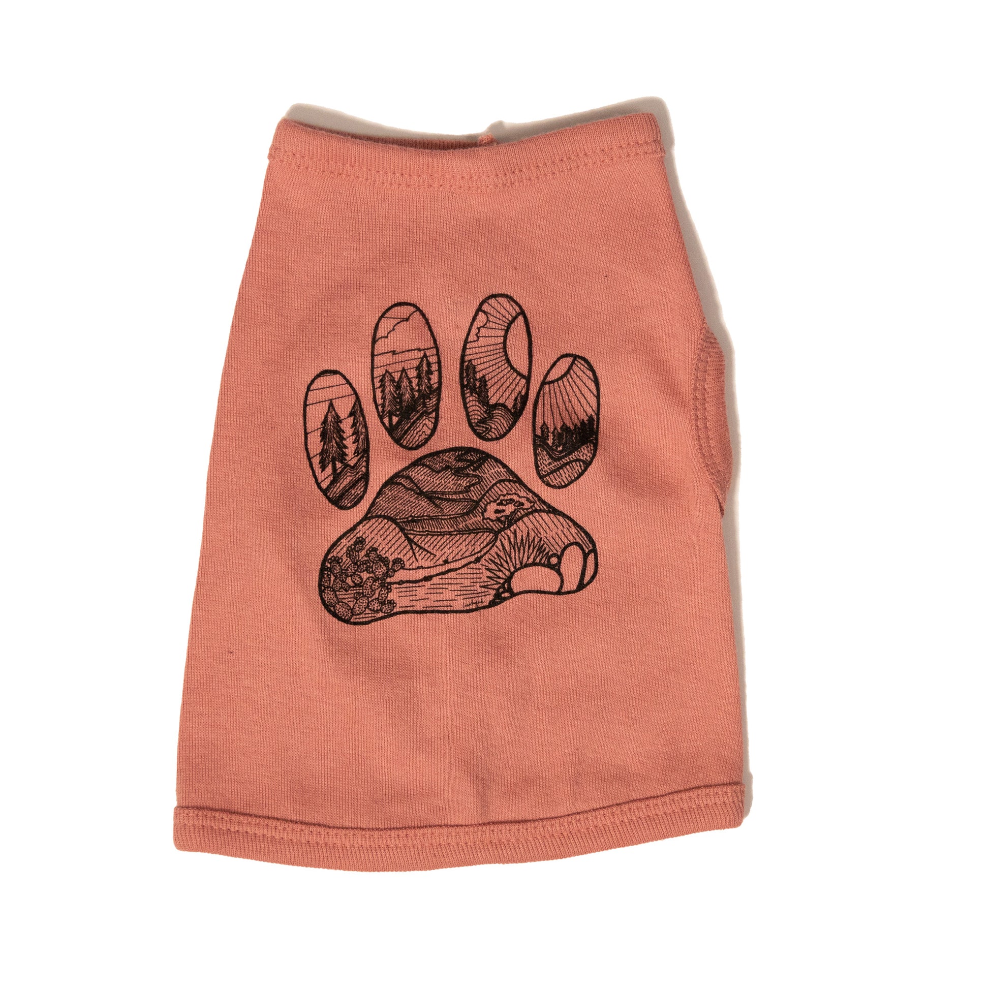 A mauve color dog shirt in a tank top style. The illustrated design on the back features a desert floor leading up to mountains with pine trees. The design is inside the shape of a dog paw print. The illustration is in black and the shirt color is mauve.