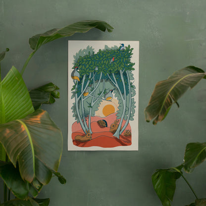 An illustrated print hangs on a green wall that has large green leaves from plants in front of it. This 11"x17" print of animal characters found in a graythorn bush. Quail, cottontail bunnies, Western scrub jay, house finches, and a desert tortoise all hang out inside and underneath the branches of this bush. A sun can be seen setting in the background through an opening in the branches.