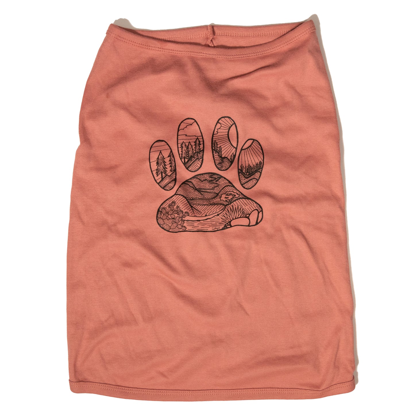 A mauve color dog shirt in a tank top style. The illustrated design on the back features a desert floor leading up to mountains with pine trees. The design is inside the shape of a dog paw print. The illustration is in black and the shirt color is mauve.